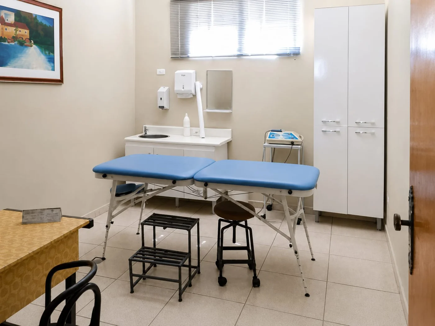 Sala de atendimento com maca, mesa e cadeiras